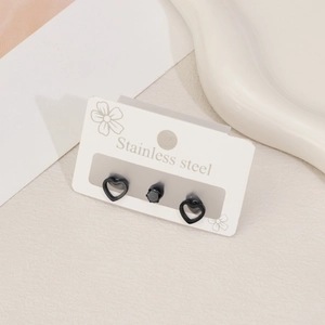 Detail view of black stainless steel heart and crystal stud earrings on white card