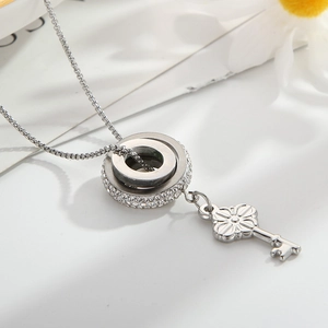 Detail of silver key necklace with interlocking pave rhinestone rings on white background