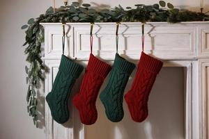 Classic knitted Christmas stockings in red and green hanging on a decorated white fireplace