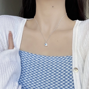 Close-up of 925 sterling silver necklace with blue heart zircon padlock pendant on a model