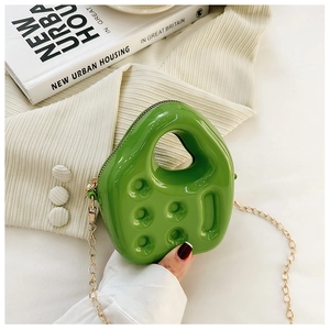 Detail of green jelly PVC handbag with golden chain strap and textured surface accents