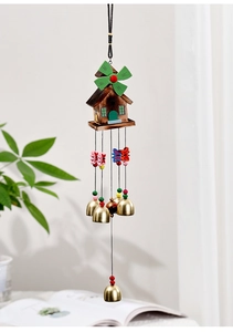 Detail of wooden cartoon house wind chime with metal bells and green windmill leaves