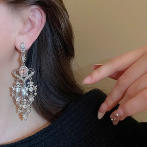 Close-up of dangling silver tassel earring with pink oval stone and sparkling rhinestones