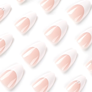 White French press-on nails with almond shape, peach base, and pearl bear accents