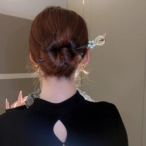 Close-up of vintage wooden hair stick with floral tassels worn in an elegant bun hairstyle