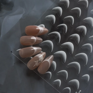 Detail of nude almond press-on nails with white French tips and elegant rose pattern