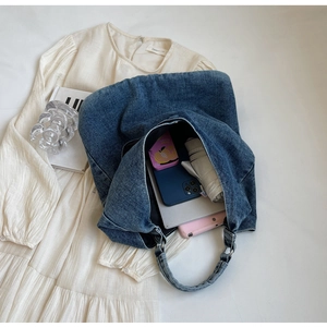 Top-down view of a spacious blue denim tote bag with daily essentials inside showing high capacity