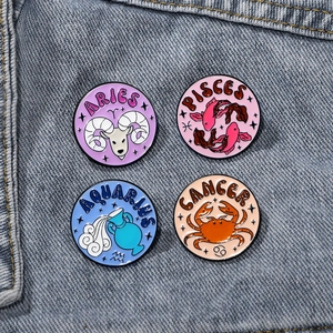 Zodiac enamel pin set featuring Aries Pisces Aquarius Cancer on blue denim fabric