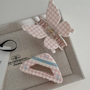 Detailed view of pink gingham hair claw clip and floral triangle hairpin on grey linen