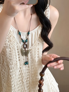 Detail of bohemian butterfly pendant with wood beads on long brown waxed cord