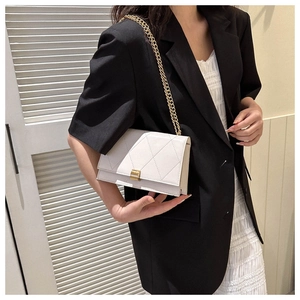 Close-up of a white quilted crossbody bag with a gold metal chain and clasp closure