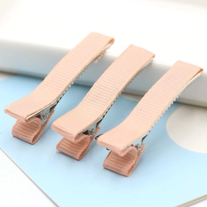 Detailed view of three pink ribbed fabric duckbill hair clips on blue display card
