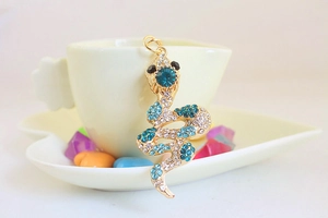 Close-up of golden snake keychain featuring blue gemstones and white rhinestones