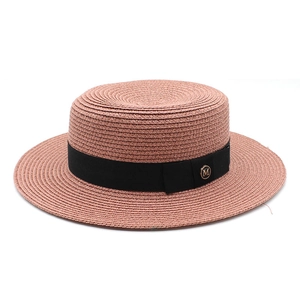 Détail d'un chapeau canotier rose avec ruban noir et boucle dorée arborant le logo M