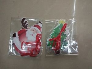 Close-up of Santa Claus and Christmas tree paper tags with red ribbons in packaging