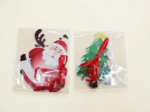 Close-up of Santa Claus and Christmas tree paper tags with red ribbons in packaging