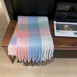 Macro view of pastel plaid scarf texture featuring soft fringes and colorful woven pattern