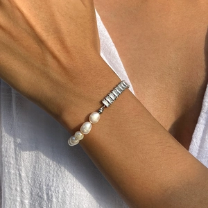 Detailed view of pearl and zircon patchwork bracelet on female wrist with silver finish