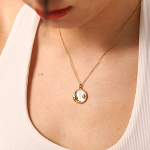 Detail of 18K gold stainless steel necklace with white shell moon and star pendant