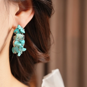 Gros plan de pierres turquoise bleues irrégulières tissées dans une boucle d'oreille en C