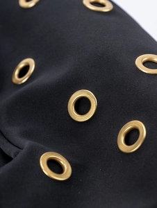 Macro view of gold eyelet rivets on black high-density fabric of the suede shoulder bag