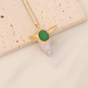Detail of vintage bull head pendant necklace with green gemstone on beige textured stone