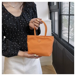 Détail d'un sac seau en nylon orange avec logo embossé circulaire en forme de m