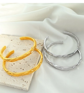 Detail view of irregular hammered gold and silver open cuff bracelets on stone