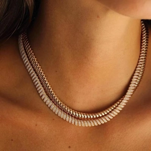 Close-up of 10mm wide gold layered tennis chain and twisted link necklace on a model