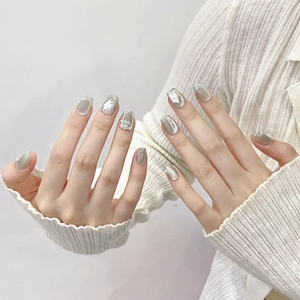 Cat eye press-on nails in grey-green with flower patterns and pearl accents on hand