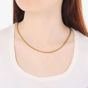 Golden stainless steel wheat chain necklace worn by a model against a white background