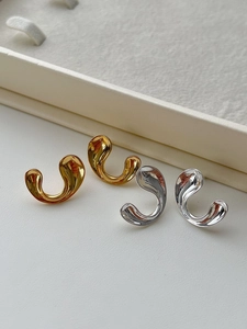 Detailed close-up of polished gold and silver C-shape earrings on a jewelry display box