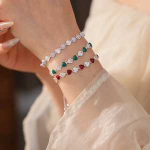 Detail of stacked vintage heart bracelets with colorful zircon stones on a female wrist