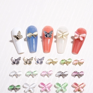 Makroaufnahme von 3D-Schmetterling-Nagelcharms mit Katzenaugensteinen und Metallstruktur