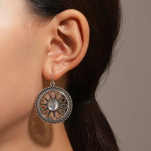 Close-up of vintage silver floral drop earrings with translucent gemstone on a model