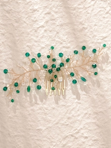 Detailed close-up of gold leaf hair comb with green crystals and sparkling beads