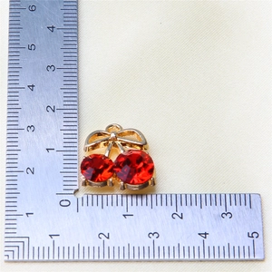 Close-up of red crystal cherry pendant with golden alloy base showing 1.5cm scale size