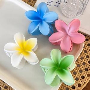 Summer plumeria hair claws in four colors for beach vacations on a white tray