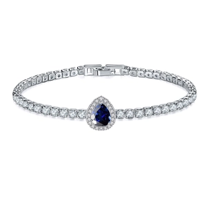Detailed macro of a tennis bracelet with a pear-shaped blue stone and silver metal