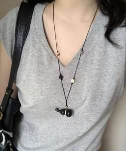 Close-up of black gourd pendant on rope necklace with pearl bead accents and vintage style