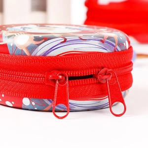 Close-up of red Christmas tin coin purse showing dual metal zipper and festive holiday pattern