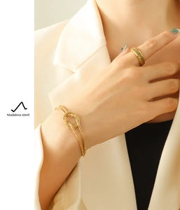 Detail showing a gold-plated stainless steel knot bracelet and textured wide ring on a model