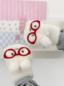 Detailansicht der flauschigen weißen Fäustlinge mit roter Brille und Stickerei