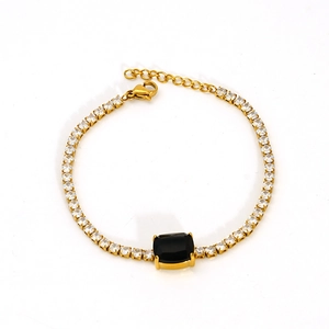 Macro detail of gold tennis bracelet with black rectangular gem and lobster clasp