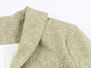 Close-up detail of green tweed texture and lapel structure of the women blazer