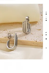 Macro detail of silver U-shaped triple bar earrings on elegant silk and stone background