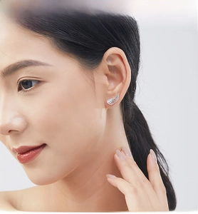 Close-up of elegant S925 sterling silver angel wing stud earrings on a model's ear
