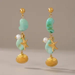 Gold stainless steel starfish earrings with green stones and pearls on white background
