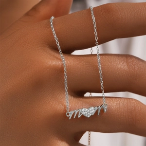 Macro shot of silver MOM necklace with a sparkling pavé heart pendant in human hand
