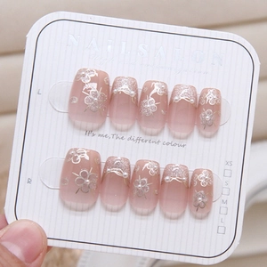 Close-up of handmade cat-eye press-on nails with silver flowers and pearls on display card